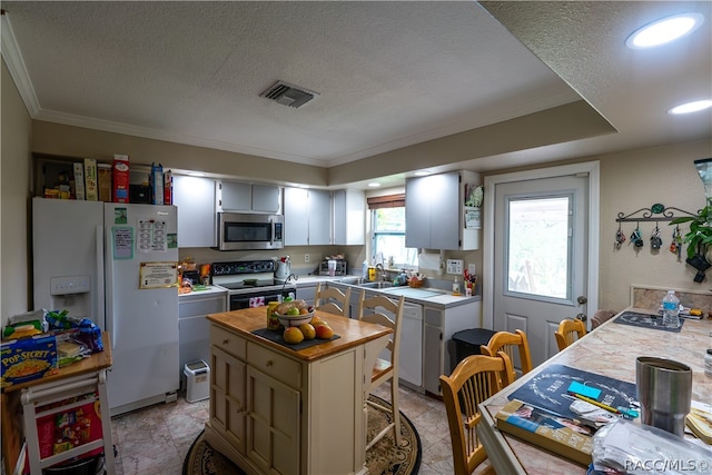 kitchen with appliances with stainless steel finishes, a textured ceiling, crown molding, sink, and a center island