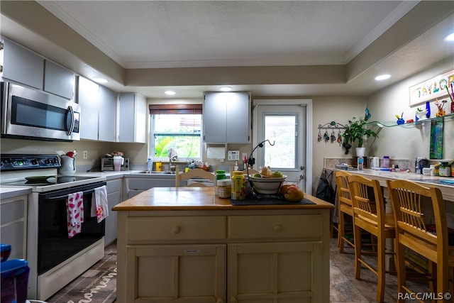 kitchen with white electric range, a center island, and ornamental molding