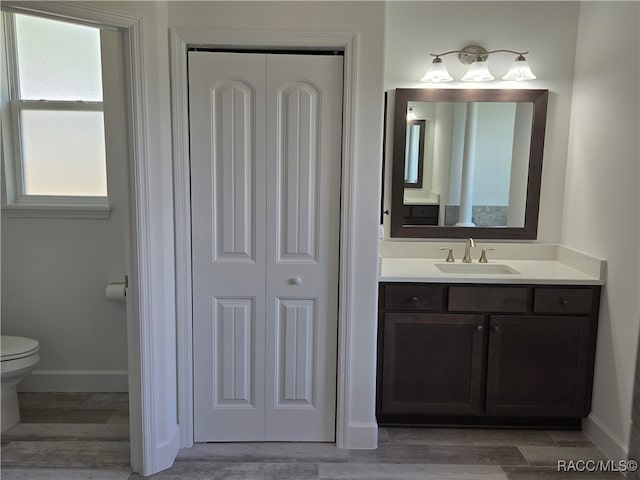 bathroom with toilet, vanity, and hardwood / wood-style flooring