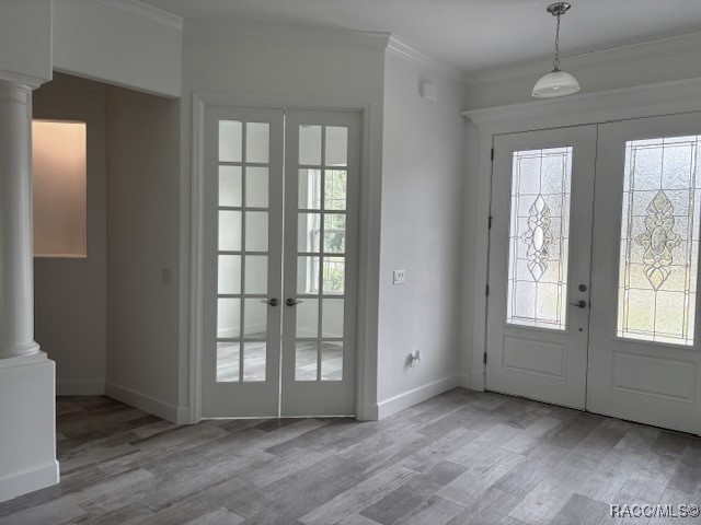 foyer entrance featuring ornate columns, crown molding, french doors, and light hardwood / wood-style floors