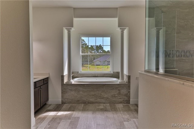 bathroom featuring hardwood / wood-style flooring, vanity, separate shower and tub, and ornate columns