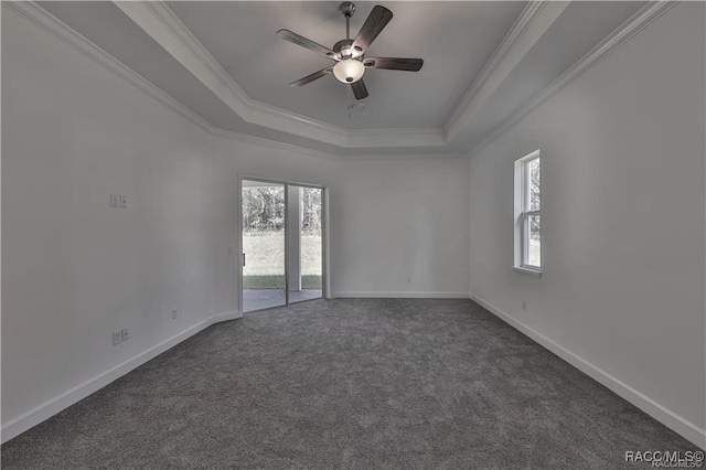 spare room featuring a tray ceiling, dark carpet, ceiling fan, and ornamental molding