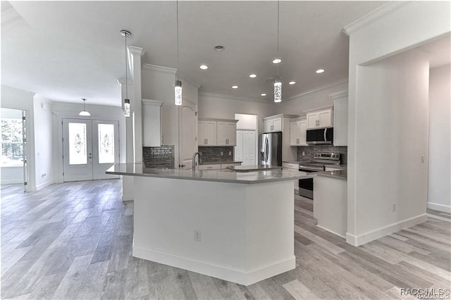 kitchen with pendant lighting, light wood-type flooring, stainless steel appliances, and french doors