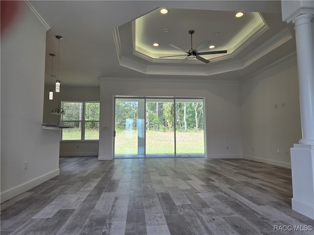 spare room with hardwood / wood-style floors, ceiling fan, ornamental molding, a tray ceiling, and decorative columns