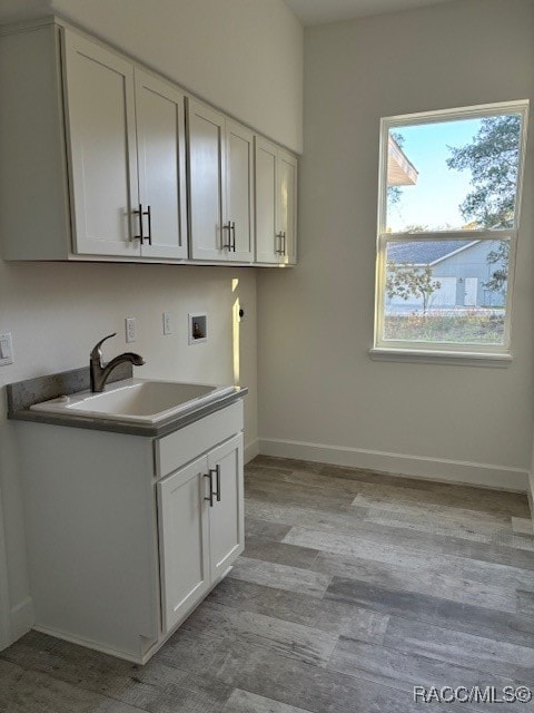 laundry area featuring cabinets, hookup for a washing machine, light hardwood / wood-style floors, and sink