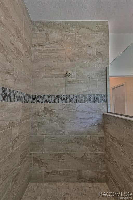 bathroom featuring a textured ceiling and tiled shower