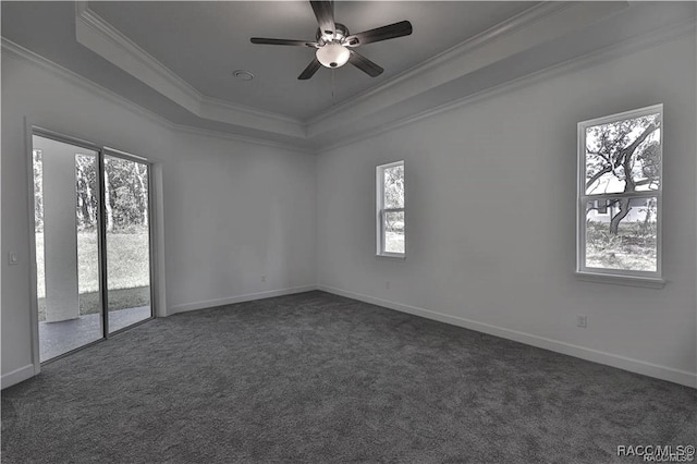 empty room featuring dark colored carpet, a raised ceiling, and ornamental molding