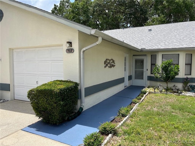 717 Whispering Pines Blvd, Inverness, FL 34453 - property entrance with an attached garage, roof with shingles, stucco siding, and a yard