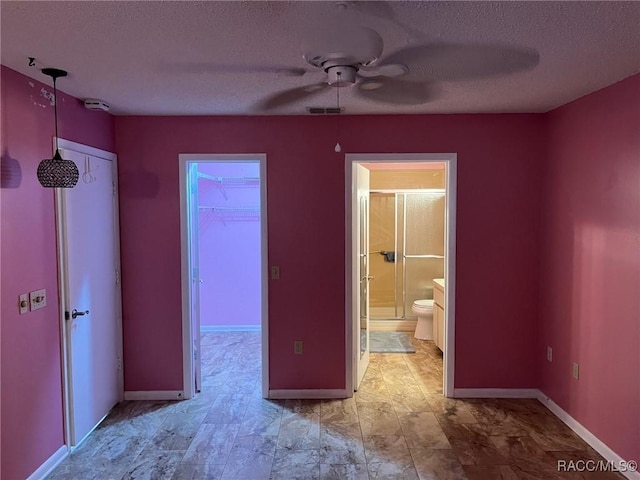 717 Whispering Pines Blvd, Inverness, FL 34453 - unfurnished bedroom with a textured ceiling, ensuite bathroom, a spacious closet, a closet, and ceiling fan
