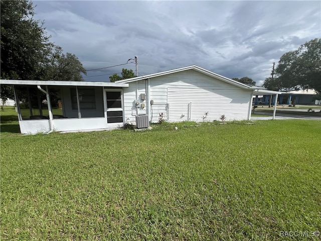 view of side of property with a yard, cooling unit, and a carport