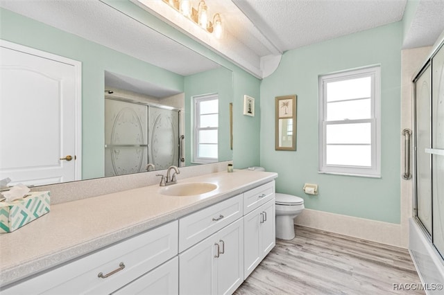 full bathroom featuring hardwood / wood-style floors, a textured ceiling, toilet, shower / bath combination with glass door, and vanity