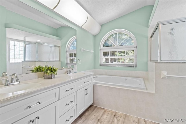 bathroom featuring lofted ceiling, a textured ceiling, a sink, a shower stall, and double vanity