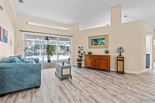 living room with light hardwood / wood-style floors, a textured ceiling, and a high ceiling