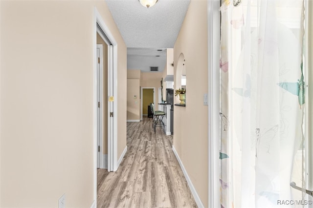 corridor with light hardwood / wood-style floors and a textured ceiling