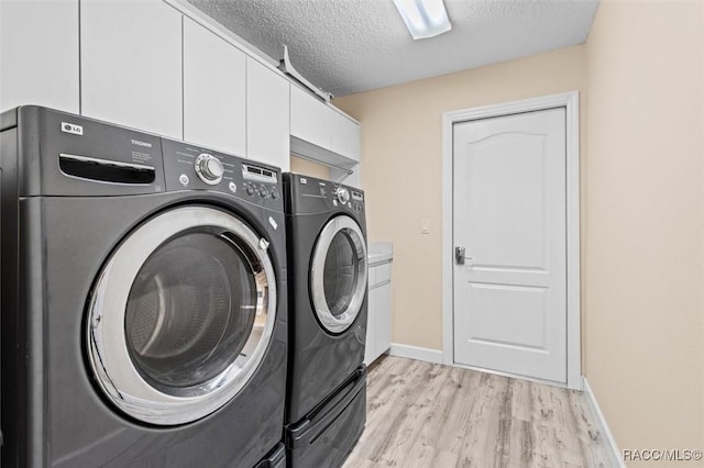 laundry room with washer and clothes dryer, light wood finished floors, cabinet space, a textured ceiling, and baseboards