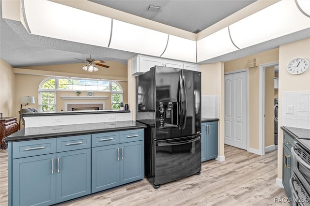 kitchen featuring backsplash, black fridge, light hardwood / wood-style flooring, and a textured ceiling