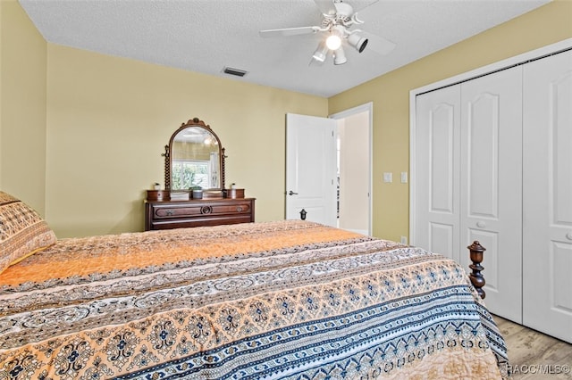 bedroom featuring ceiling fan, a closet, light hardwood / wood-style floors, and a textured ceiling