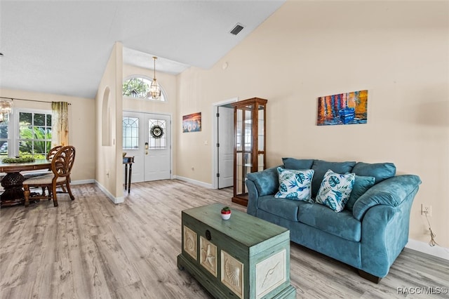 living room featuring french doors, high vaulted ceiling, wood-type flooring, and an inviting chandelier