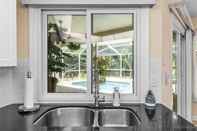 interior space featuring dark stone countertops, white cabinetry, sink, and tasteful backsplash