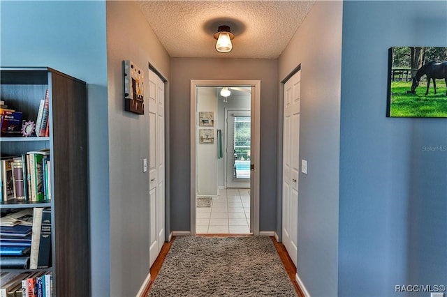 hallway featuring tile patterned flooring and a textured ceiling