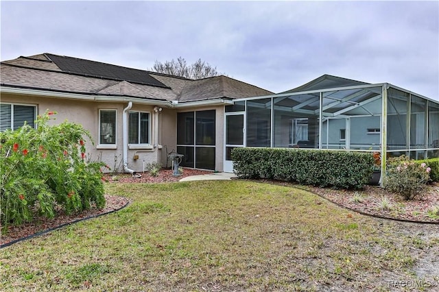 rear view of house featuring a lanai and a lawn