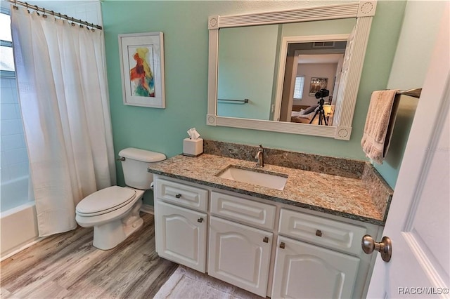 full bathroom with hardwood / wood-style flooring, vanity, toilet, and shower / tub combo