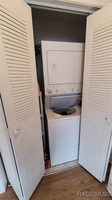 washroom featuring stacked washer / dryer and wood-type flooring