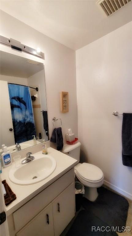 bathroom with toilet, vanity, and curtained shower