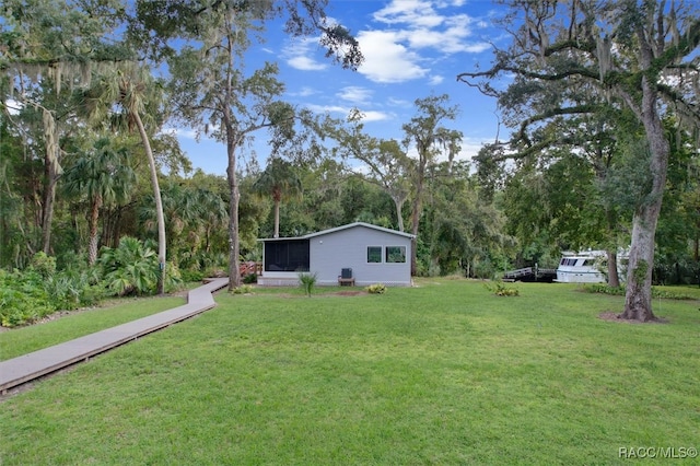 view of yard with a sunroom and a wooded view