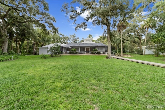 view of front facade featuring glass enclosure and a front yard