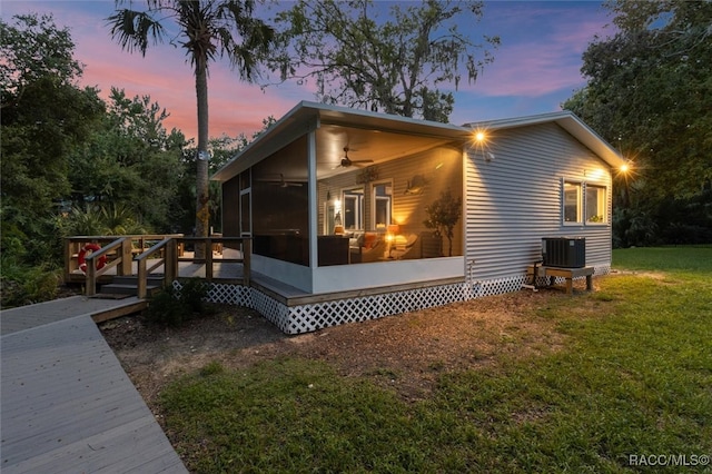 view of side of property with a lawn, a ceiling fan, a sunroom, a wooden deck, and central air condition unit