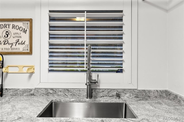 details featuring a sink and light stone countertops