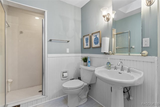 full bathroom featuring a stall shower, wainscoting, toilet, and a skylight