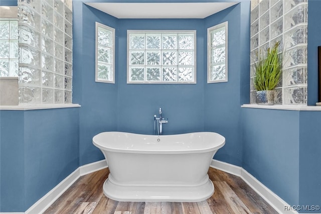 full bath featuring a freestanding tub, baseboards, and wood finished floors