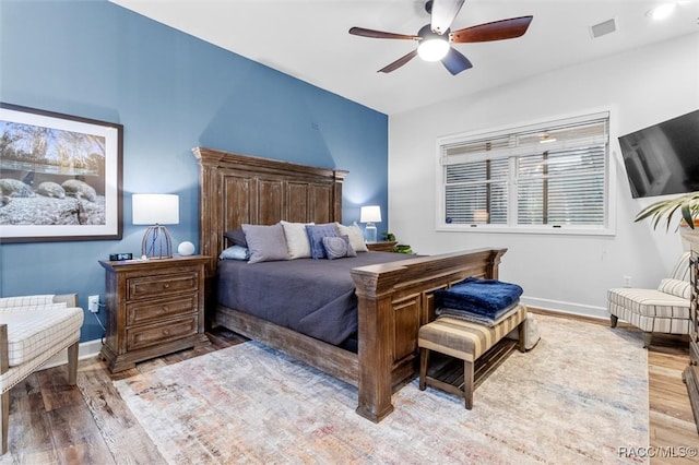 bedroom with ceiling fan, wood finished floors, visible vents, and baseboards