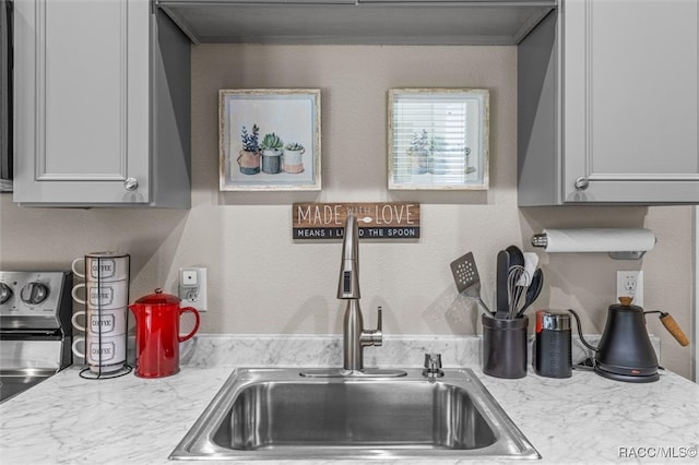 kitchen featuring a textured wall, light countertops, and a sink