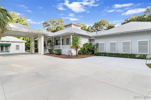 view of front of property featuring driveway, covered porch, metal roof, and a carport