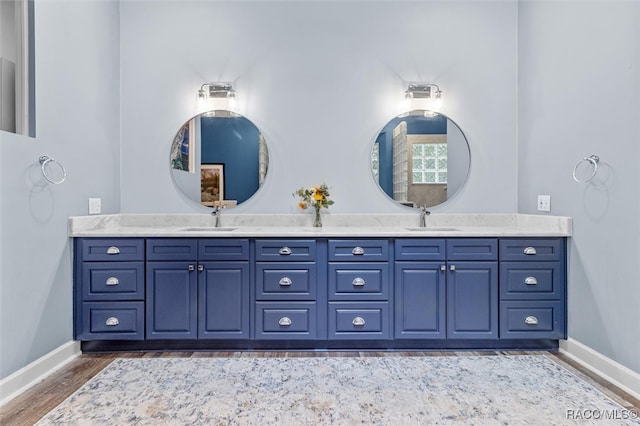 bathroom with double vanity, wood finished floors, a sink, and baseboards