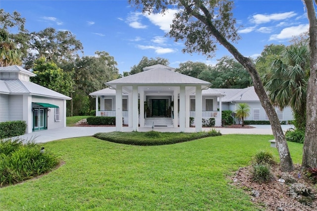 view of front of property with a front yard, covered porch, and metal roof