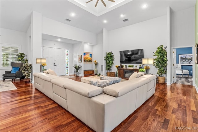 living room with recessed lighting, visible vents, a high ceiling, and wood finished floors