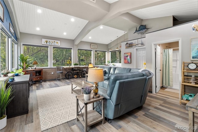 living area with lofted ceiling with beams, light wood finished floors, and a healthy amount of sunlight