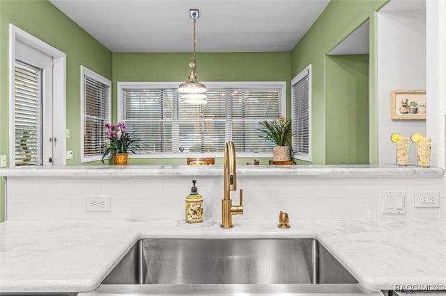 room details with light stone counters, pendant lighting, and a sink