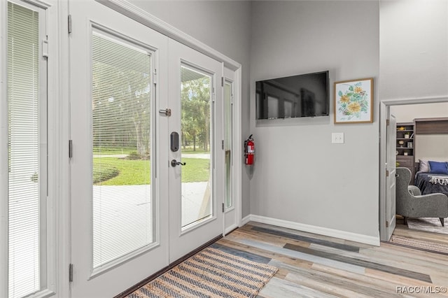 entryway featuring light wood finished floors, french doors, and baseboards