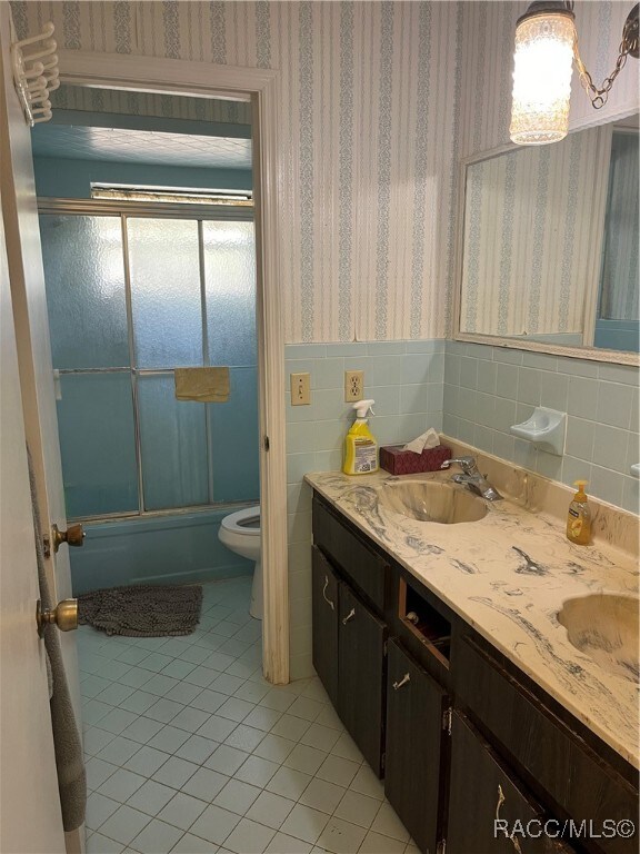 full bathroom featuring tile patterned flooring, vanity, toilet, and enclosed tub / shower combo