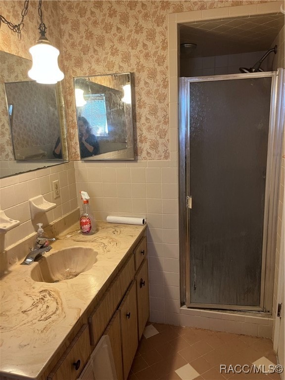 bathroom with vanity, tile patterned floors, tile walls, and a shower with shower door