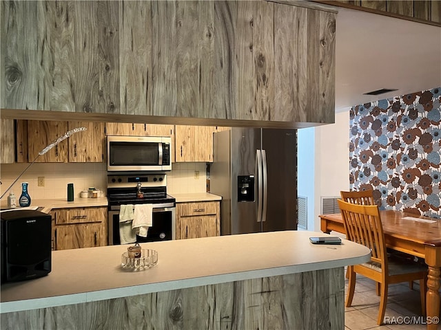 kitchen featuring light tile patterned flooring, stainless steel appliances, and tasteful backsplash