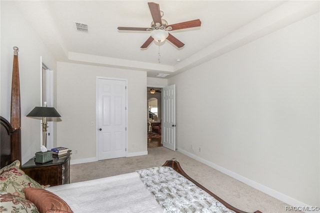 carpeted bedroom featuring ceiling fan and a raised ceiling