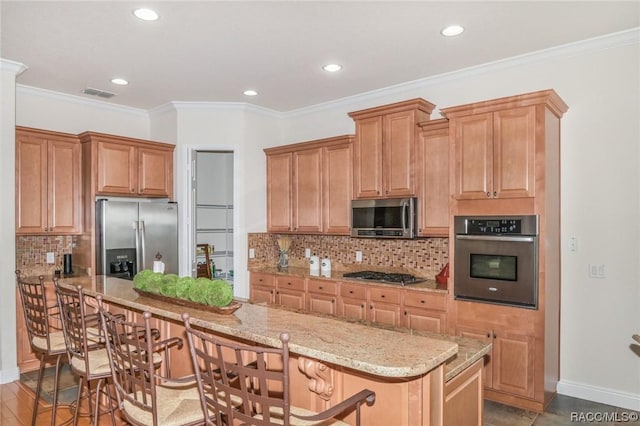 kitchen with a kitchen bar, backsplash, ornamental molding, and appliances with stainless steel finishes