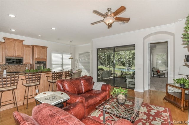 living room with crown molding, light hardwood / wood-style flooring, and ceiling fan