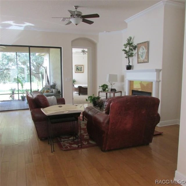 living room with hardwood / wood-style flooring, ceiling fan, and crown molding